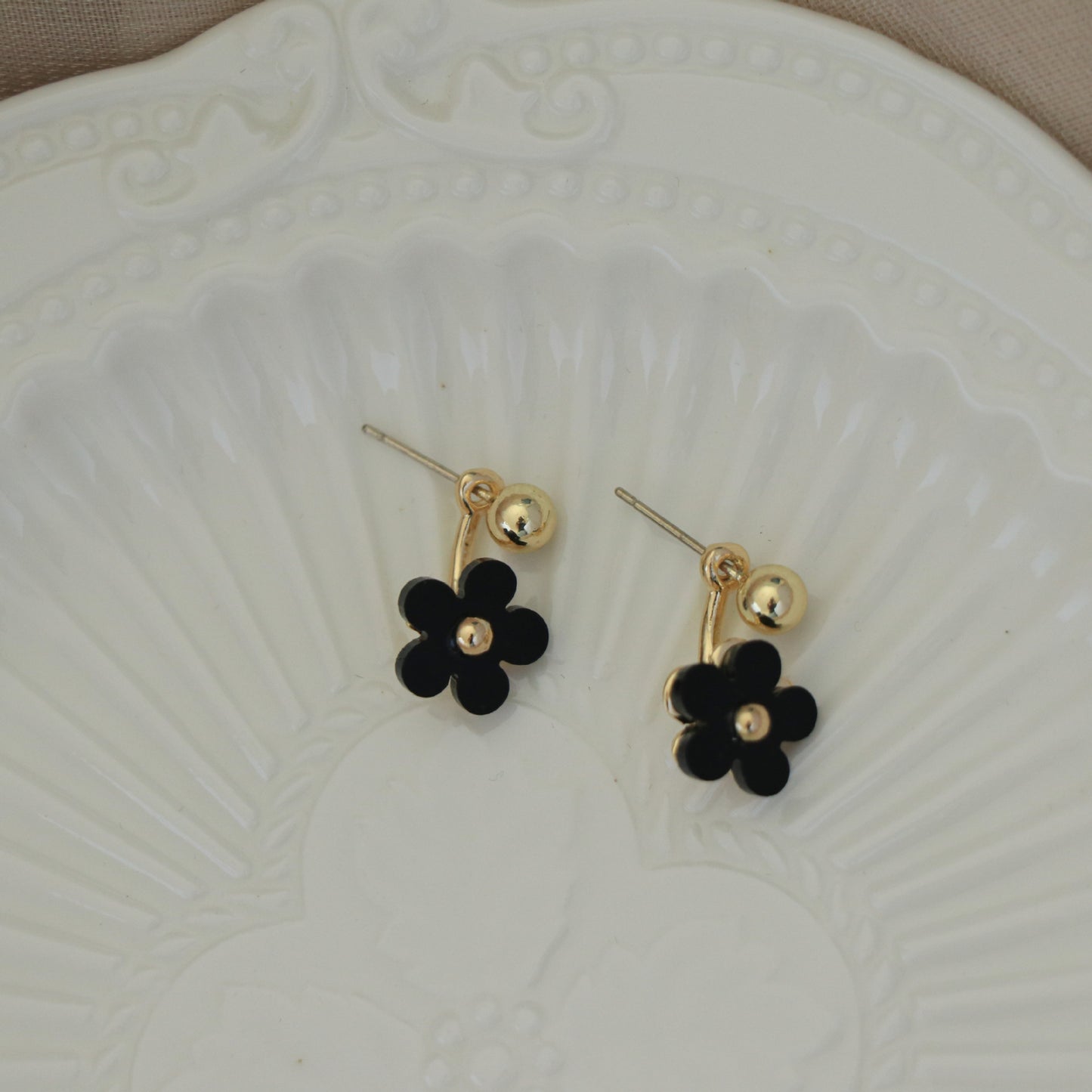 Boucles d'oreilles noires à petite fleur et mini marguerite sur le devant