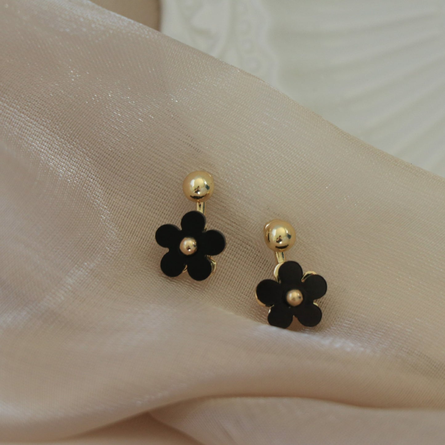 Boucles d'oreilles noires à petite fleur et mini marguerite sur le devant